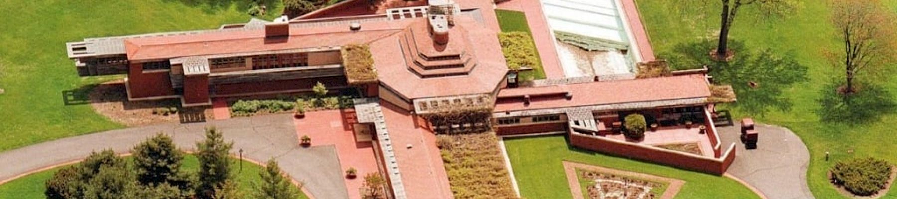 An aerial view of a large, architecturally unique building surrounded by lush greenery and landscaping.