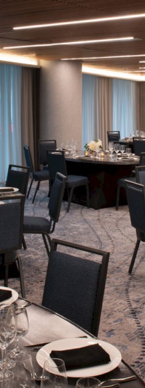 A banquet hall with round tables set for dining, featuring elegant place settings and floral centerpieces.